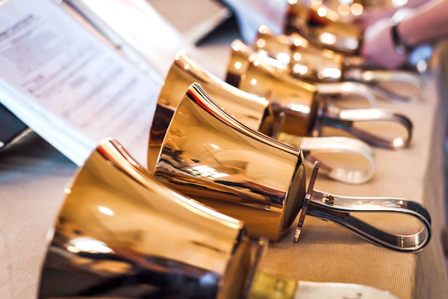 Row of shiny golden handbells on a table.