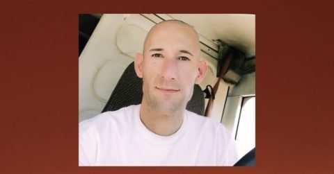 Person sitting in vehicle smiling at camera.