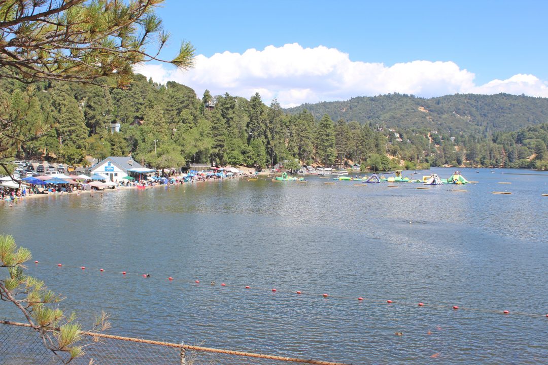 Crowded lakeside beach with forested hills background