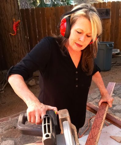 Woman using power saw for woodworking project.