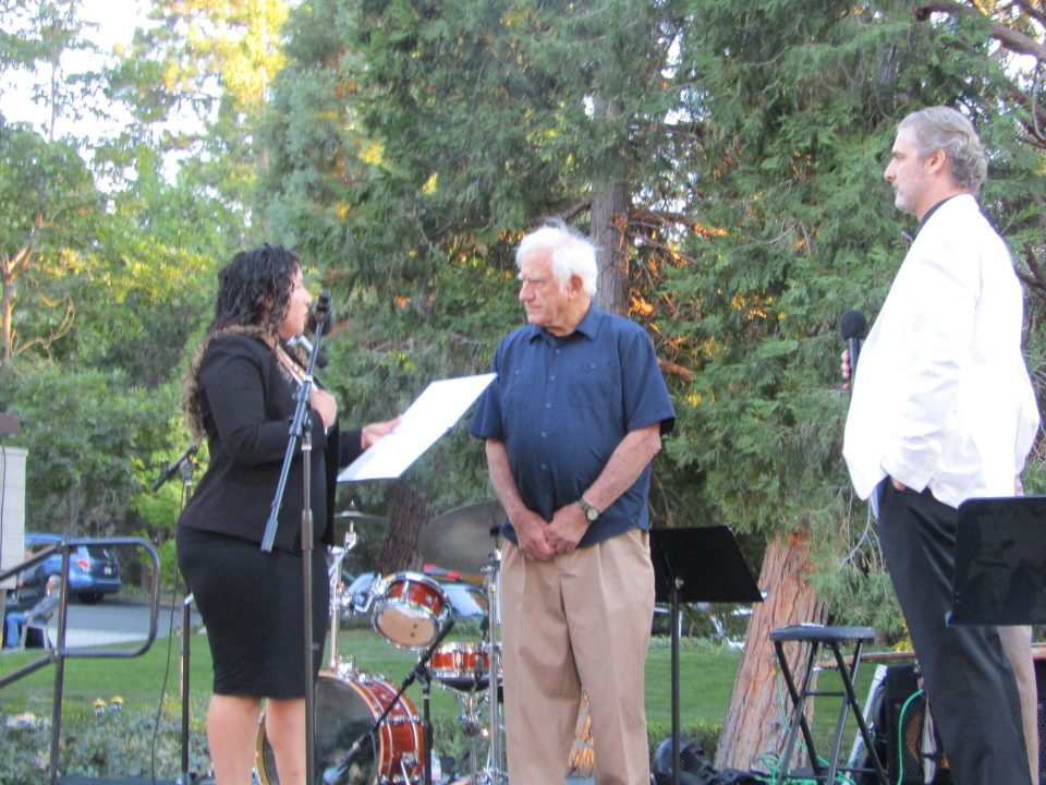 Rim Special Athletes founder/president Jack Cooperman receives a certificate from a representative of Congressman Jay Obernolte as event host Brian Cohen (right) watches.
