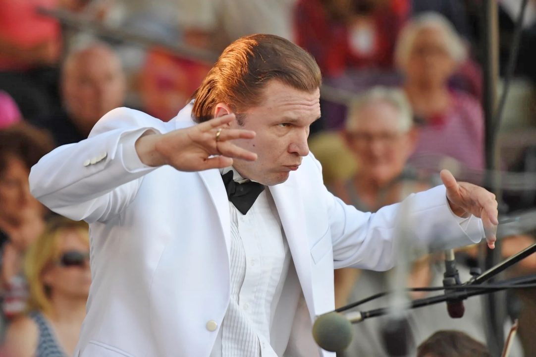 Orchestra conductor performing with intensity on stage.