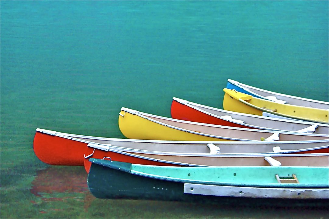 Polychrome canoes on still water at the Icefields Parkway in Alberta, Canada, are the subject of this image by the photographer.