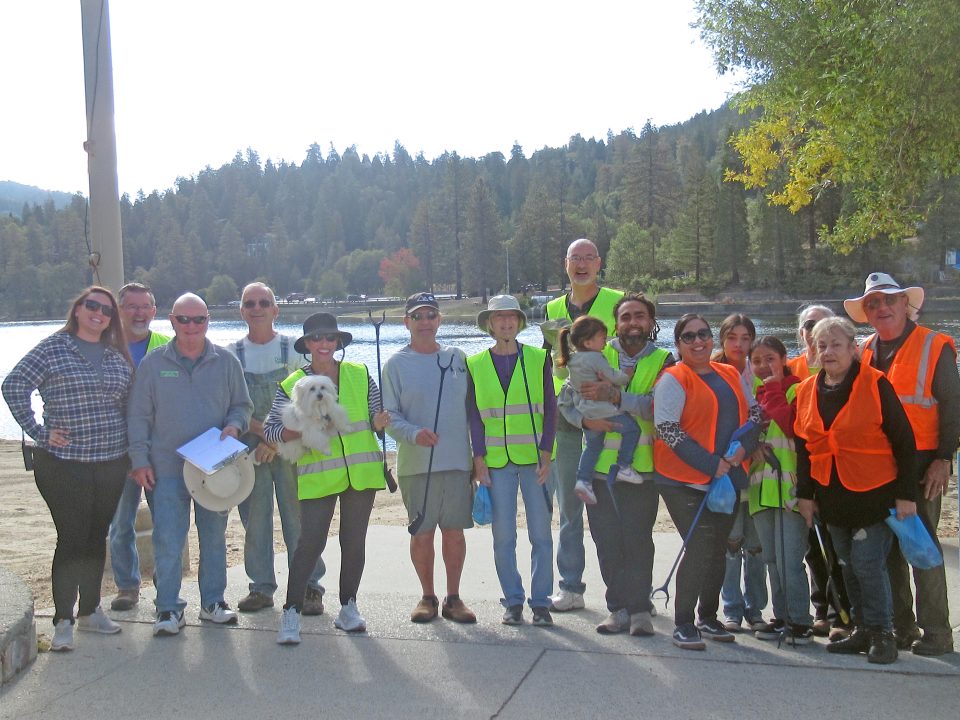 Group volunteering at lakeside in safety vests.