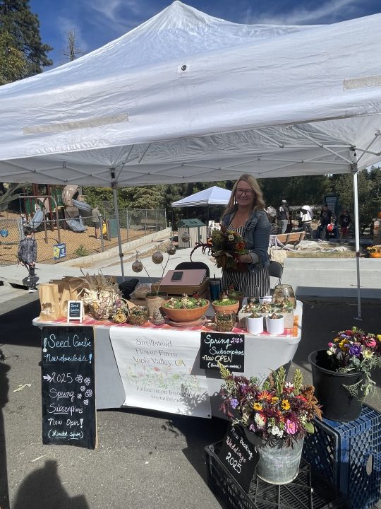 Farmers market booth with flowers and produce.