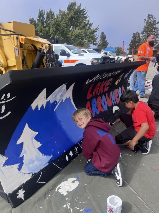 Third-grade student Miles Renberg helps to paint a mountain scene.
