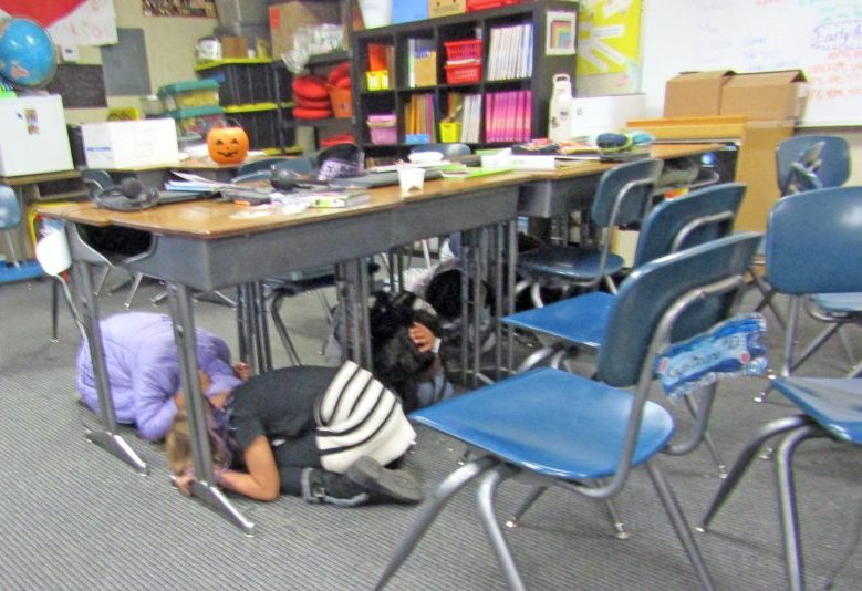 Children practicing earthquake drill under desks.