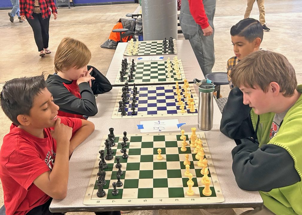 Children playing chess at a table indoors.