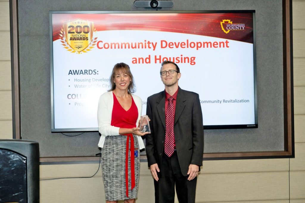 San Bernardino County Assistant Executive Officer Diane Rundles presents the 2024 NACo Achievement Award to CDH Deputy Director Evan Miles.