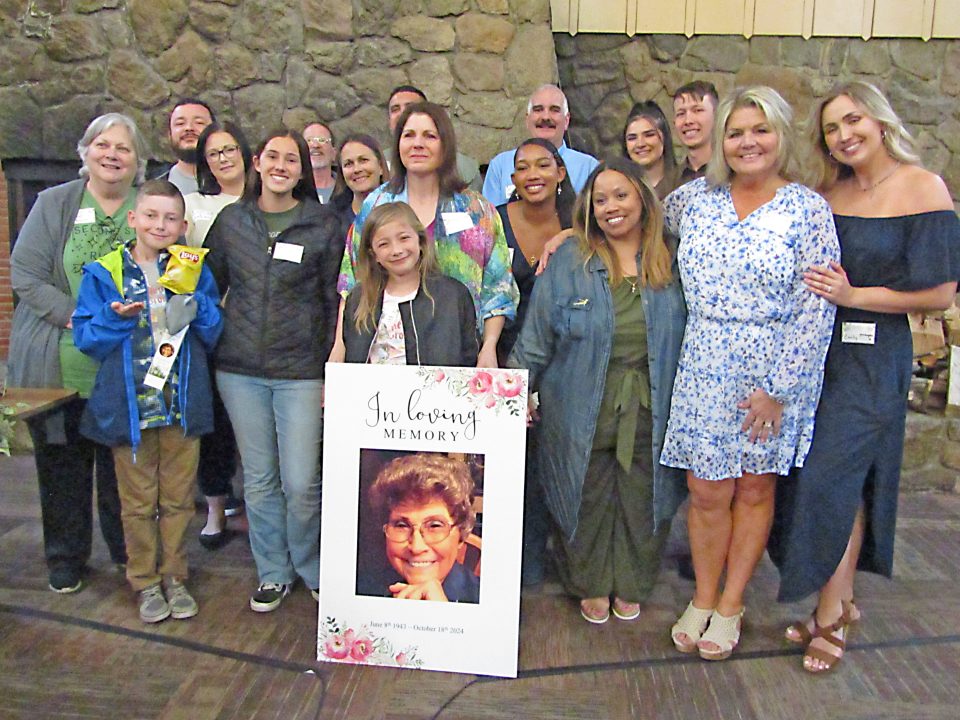 Group at memorial gathering with photo tribute.