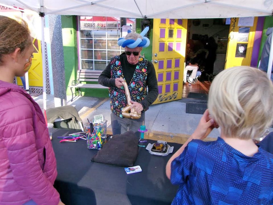 Street performer making balloon animals for children.