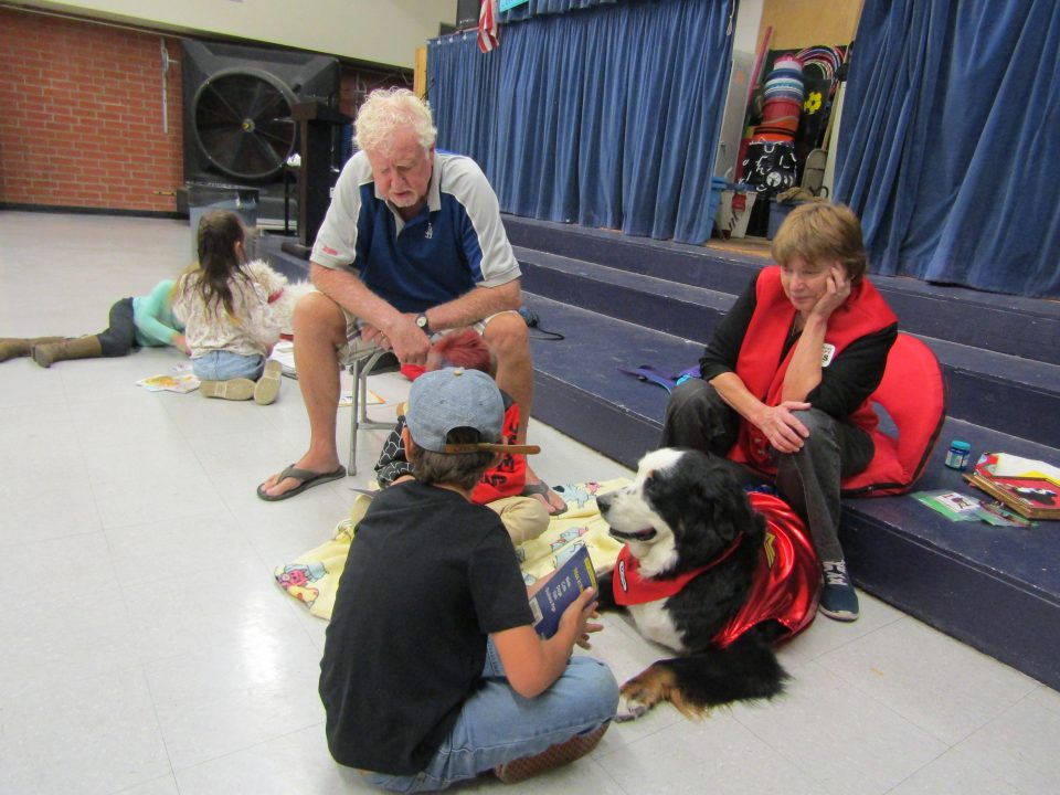 Therapy dog at reading program with children and adults.