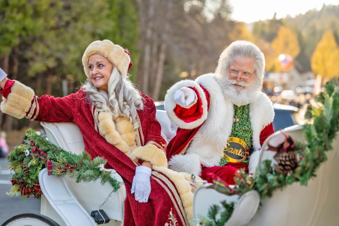 Santa and Mrs. Claus in festive carriage waving