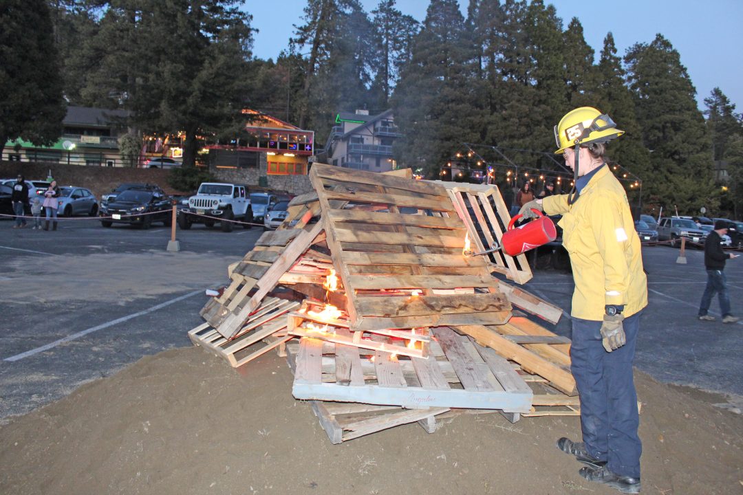 County Firefighter Morgan Greer, from Fire Station 25, begins lighting the bonfire to get the evening’s celebration started. (Photo by Mike Harris)