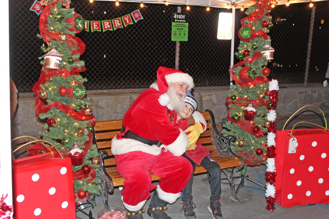 Adrianne, Lisa, Julia, Melissa and Adrianna from Glendora and Orange County enjoyed last year’s Brewfest at Tavern Bay Beach Club so much they couldn’t resist attending this year’s event. (Photos by Douglas W. Motley) Santa and child on bench, Christmas decorations around.