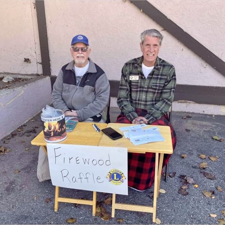 Two men running a firewood raffle table.