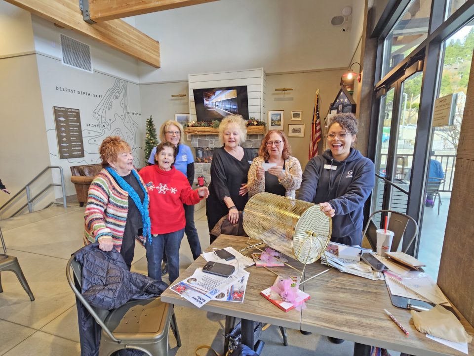 Group of women laughing around table with raffle drum.
