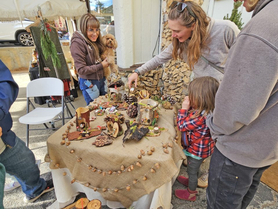 People browsing crafts at outdoor market.