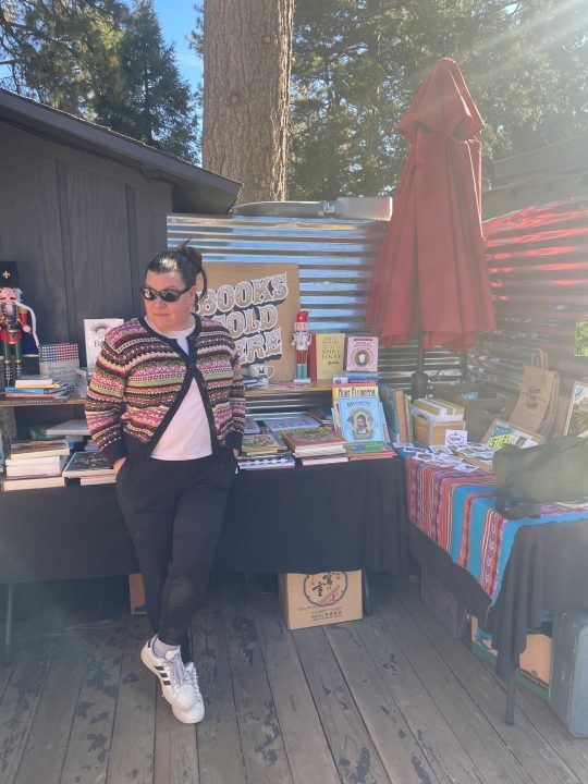 Adrianne, Lisa, Julia, Melissa and Adrianna from Glendora and Orange County enjoyed last year’s Brewfest at Tavern Bay Beach Club so much they couldn’t resist attending this year’s event. (Photos by Douglas W. Motley) Person beside outdoor book sale display.