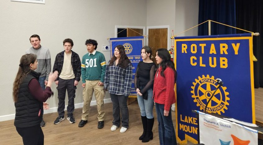 People speaking near Rotary Club banners indoors.