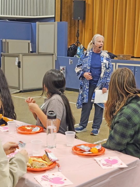Adrianne, Lisa, Julia, Melissa and Adrianna from Glendora and Orange County enjoyed last year’s Brewfest at Tavern Bay Beach Club so much they couldn’t resist attending this year’s event. (Photos by Douglas W. Motley) Older woman speaking to group at communal meal.