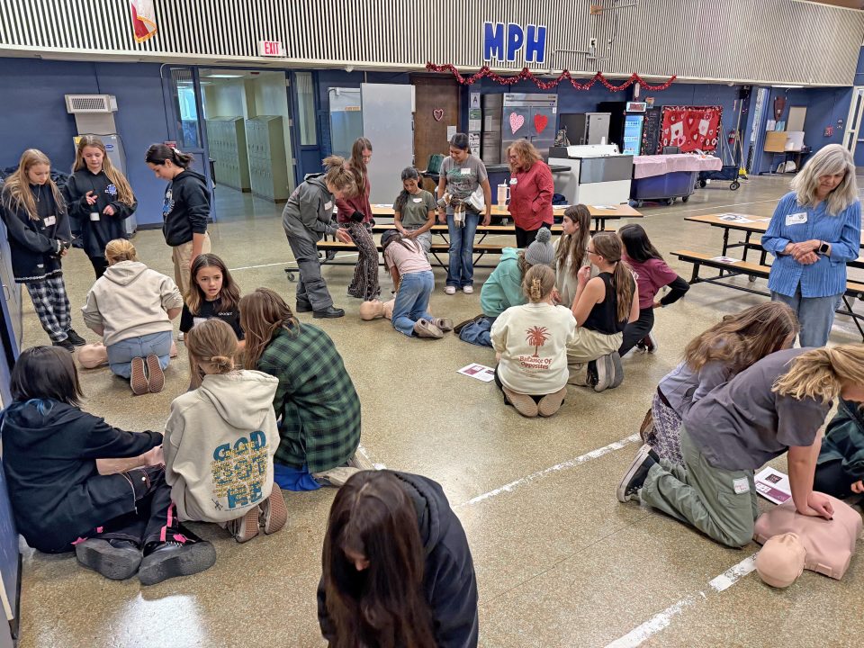 After being taken through the CPR steps by Kady Fox, the girls practiced on the mannequins she brought. (Photo by Lupe McDonald)