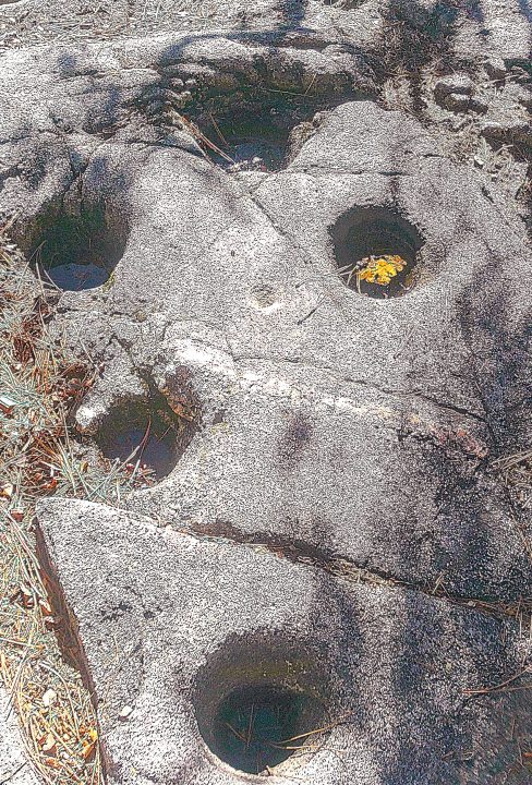 Ancient carved face rock with circular holes.