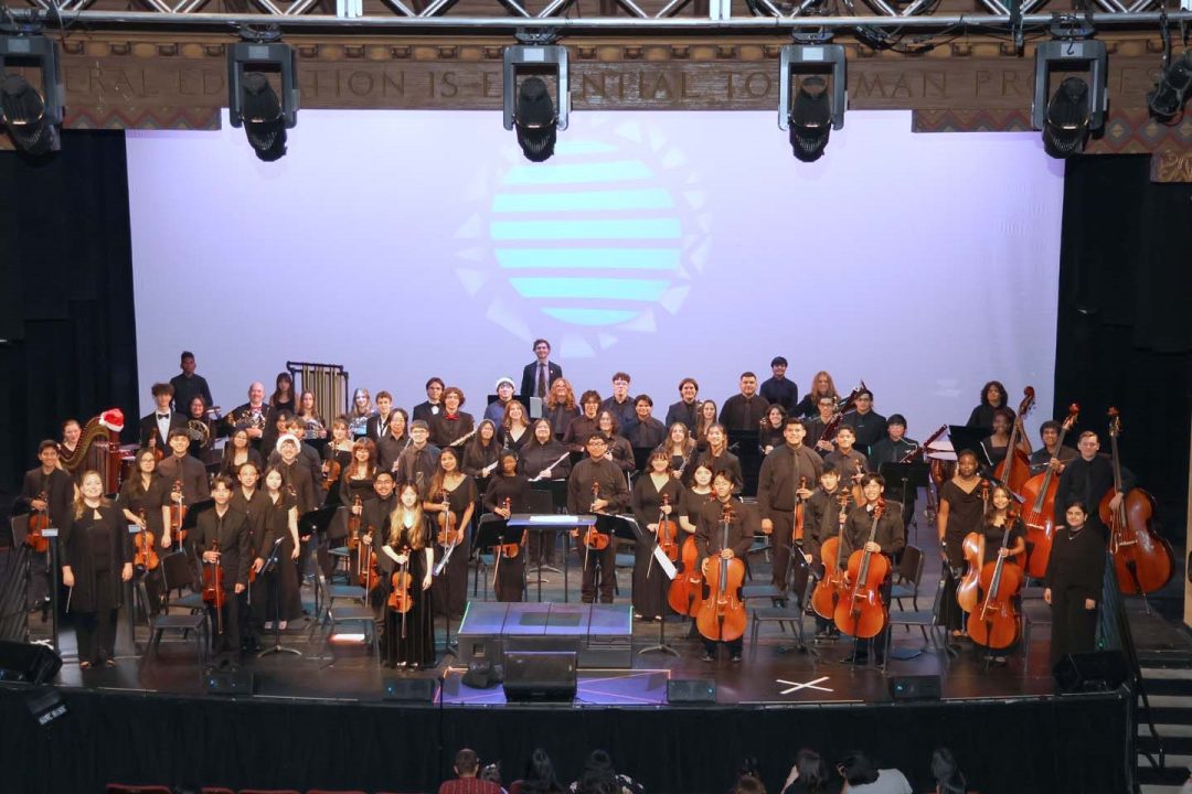 Orchestra group posing on stage with instruments.