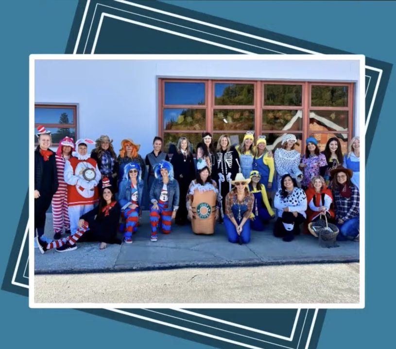 Group in colorful Halloween costumes outside building.