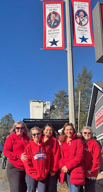 Group of women in red shirts outdoors, banners displayed.
