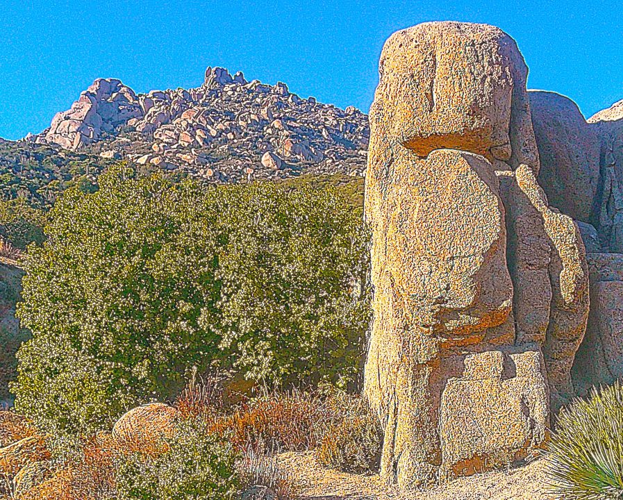 Sunny desert landscape with large rock formations.