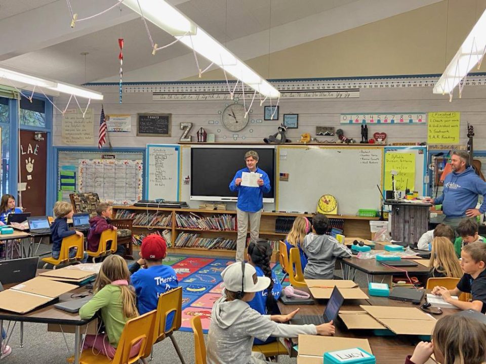Teacher presenting to classroom of students with laptops.