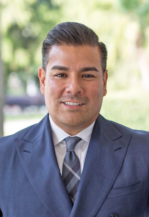 Smiling man in suit and tie outdoors.