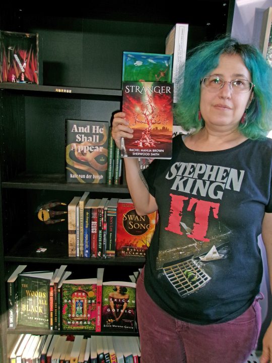 Paper & Clay bookstore owner Rachel Manija Brown holding her book that was refused by the publisher, for “content.”