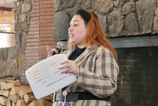 Woman speaking with microphone and holding notes.