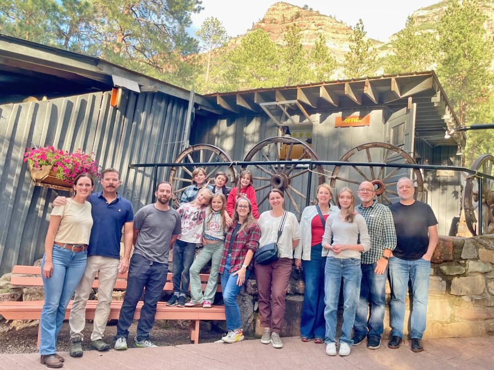 Group of people in front of rustic building.