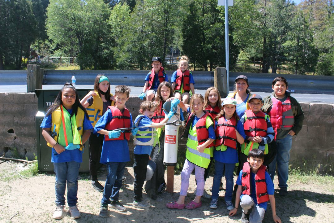 Group of kids wearing life jackets outdoors.