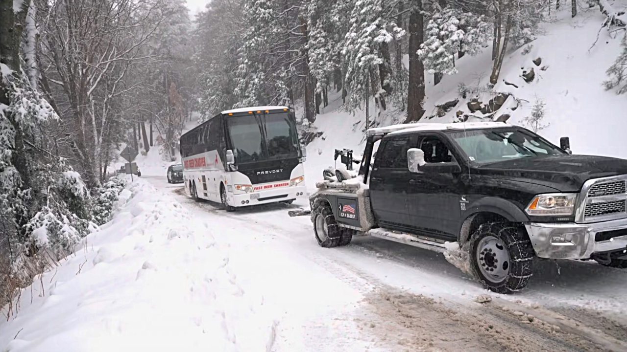 Truck towing bus in snowy forest road