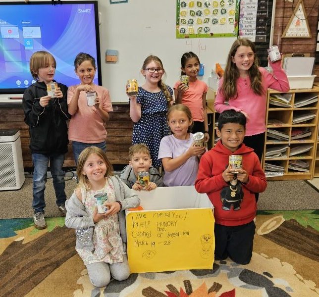 Children holding canned goods for food drive.