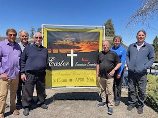Group with Easter sunrise service sign outdoors.