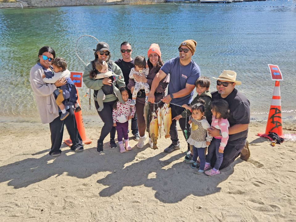 Group by lake holding freshly caught fish.