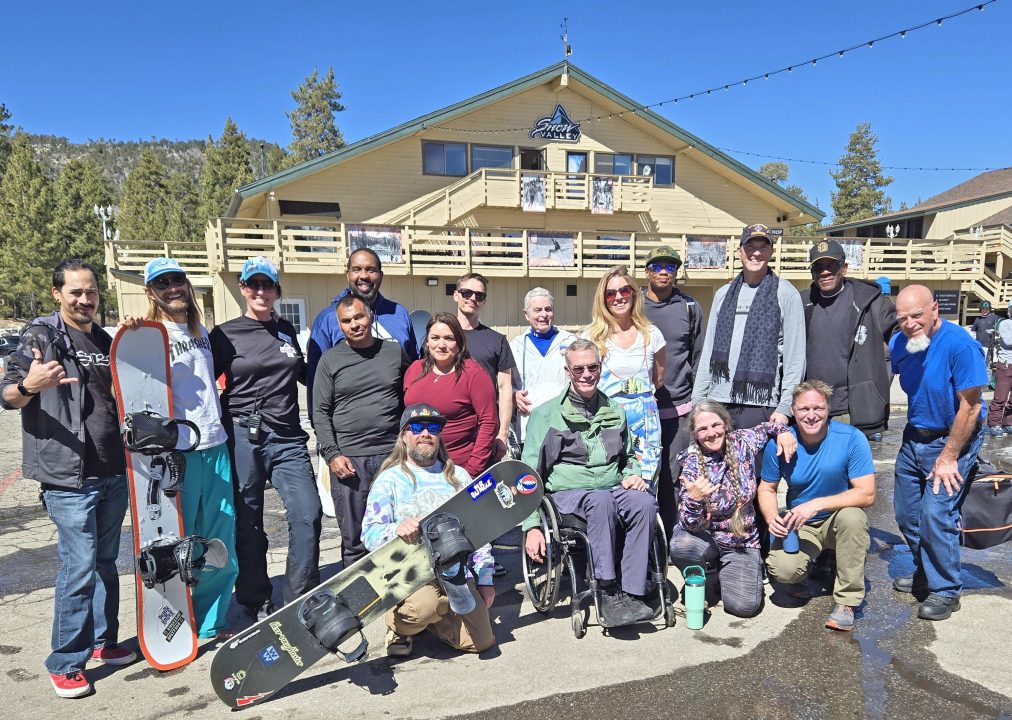 Group of snowboarders outside mountain lodge during daytime.
