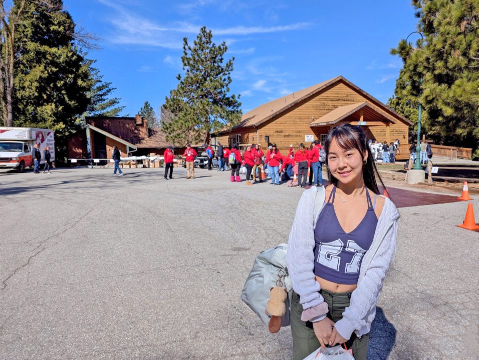 Smiling woman in front of a cabin and group.