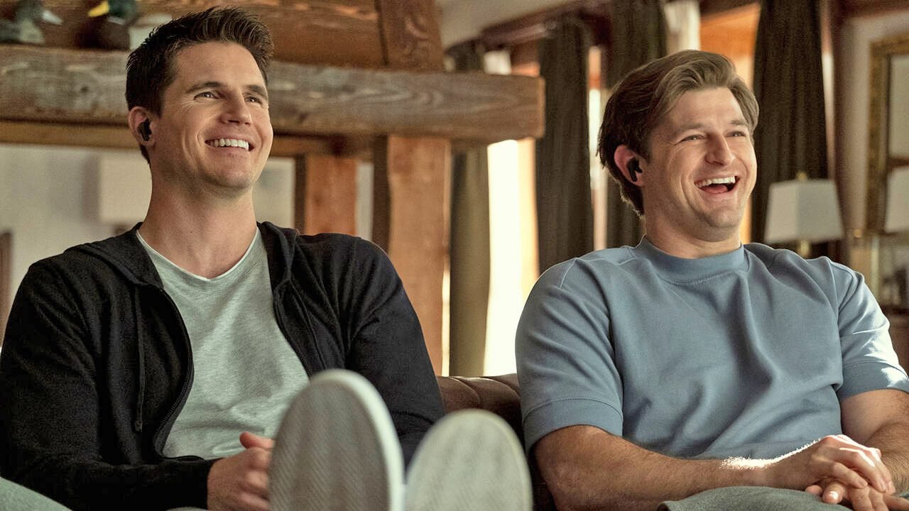 Two men laughing and sitting indoors.
