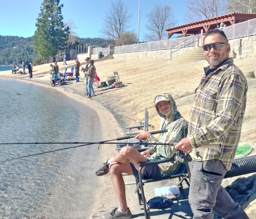 People fishing by the lakeside on a sunny day.