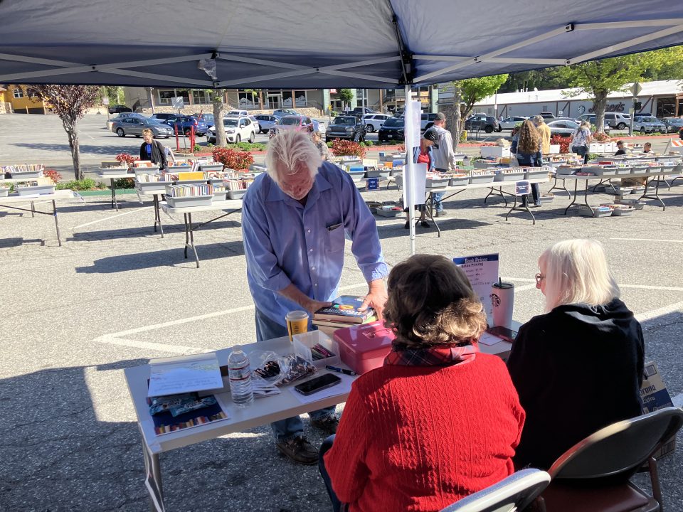 Outdoor book sale with vendors and customers.