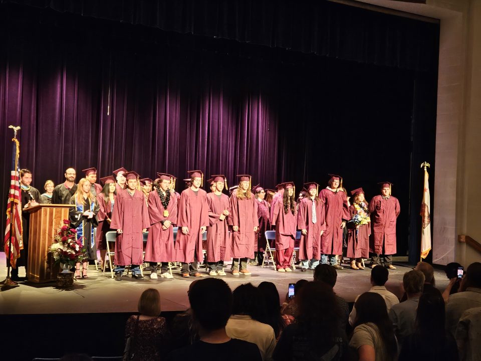Graduates in caps and gowns on stage ceremony