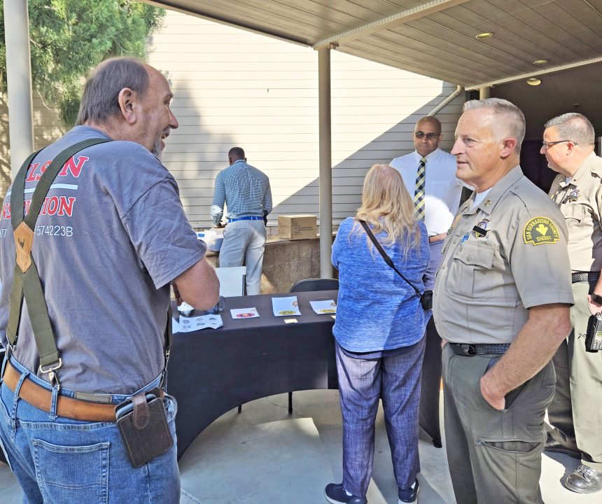 People at outdoor community event with information table.