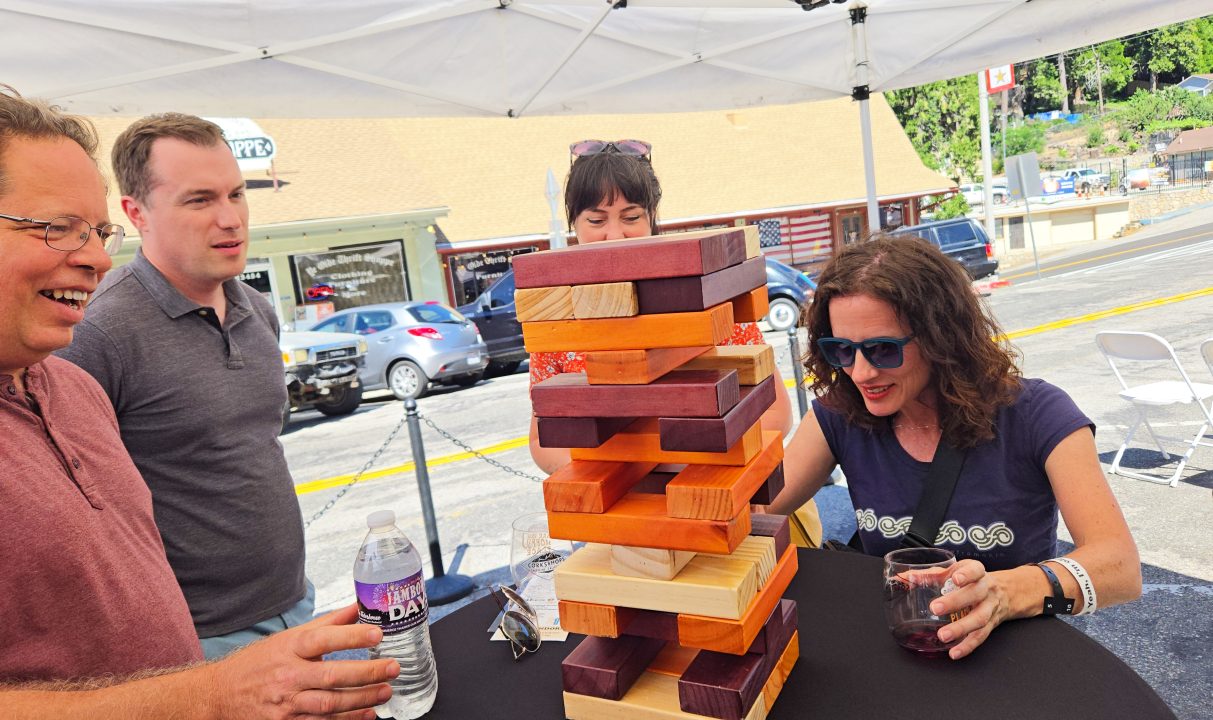 People playing giant block stacking game outdoors.