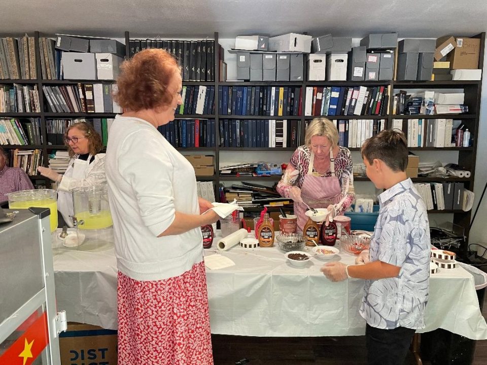 People making ice cream sundaes at a gathering.